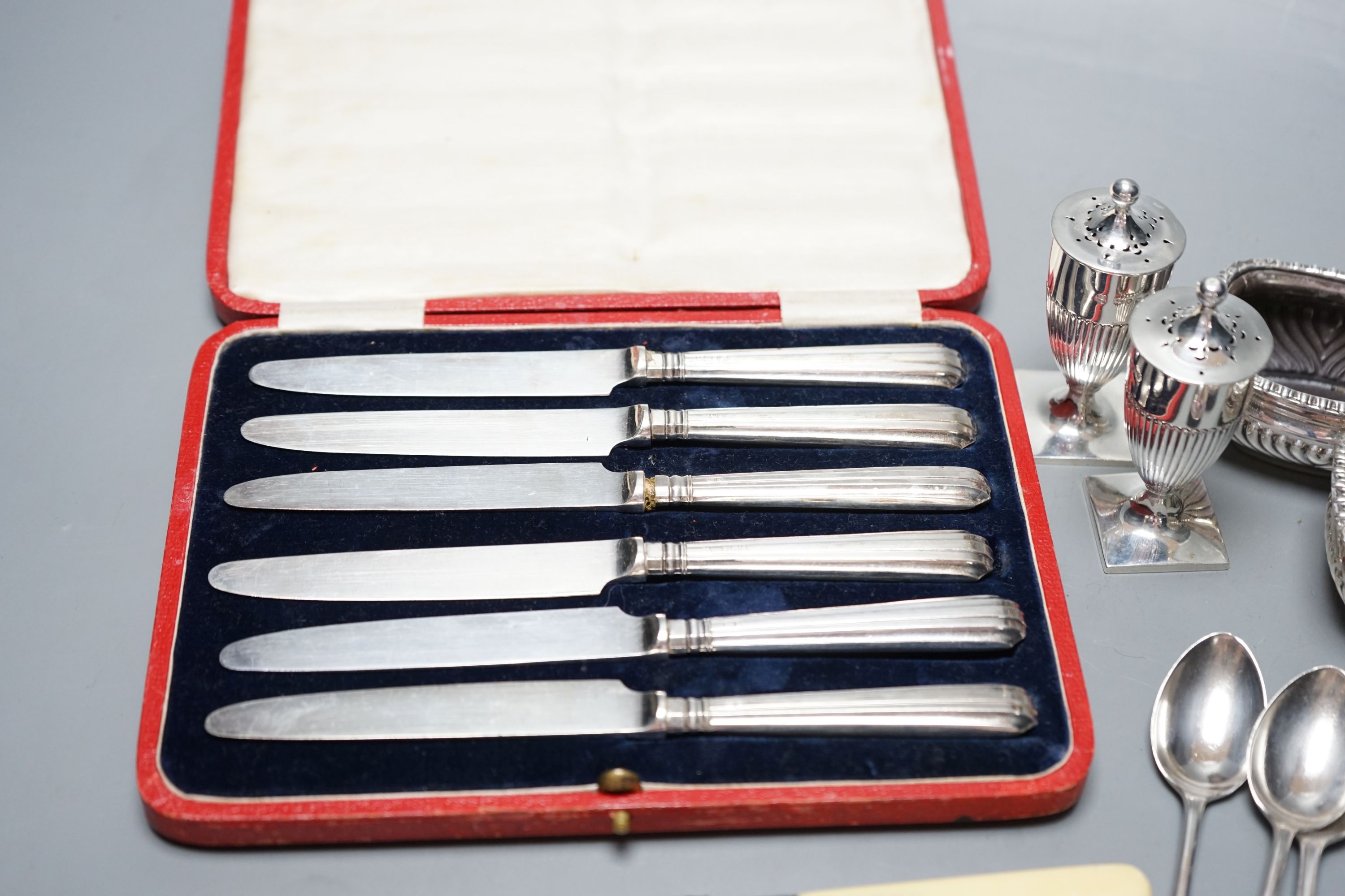 A pair of Victorian silver pepperettes, a pair of later silver salts, six silver teaspoons, a silver dessert knife and a cased set of silver handled tea knives.